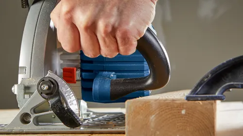 Bosch circular saw cutting wood, held by a hand.