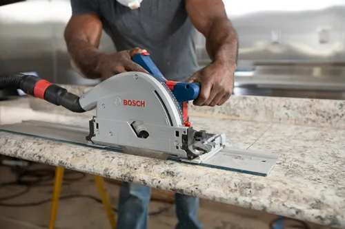 A person with Black skin, wearing a face mask, uses a Bosch circular saw on a countertop. The saw features the Bosch logo.