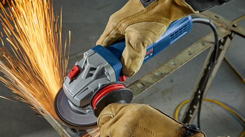 Bosch angle grinder, sparks flying, being used to cut metal bar, detail of the tool and hands wearing gloves.