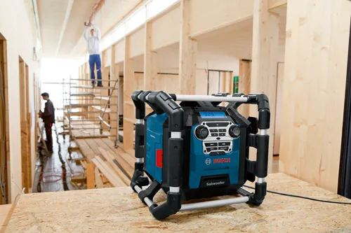 Bosch Subwoofer, blue and black, with a digital display showing "3.25" and control buttons. A worker stands on scaffolding in the background.