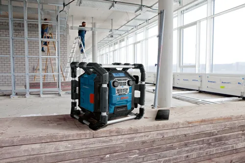 Bosch Subwoofer with 3.25 display and control buttons, next to a black smartphone, in a construction site.