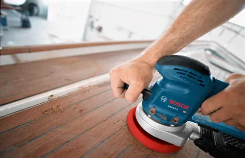 Bosch GEX33-6 sander being used on wood planks.