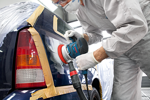 Person in protective gear using Bosch GEX 34-6 sander on a car panel.