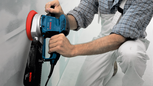 Man holding a Bosch GEX33-6 HD sander.