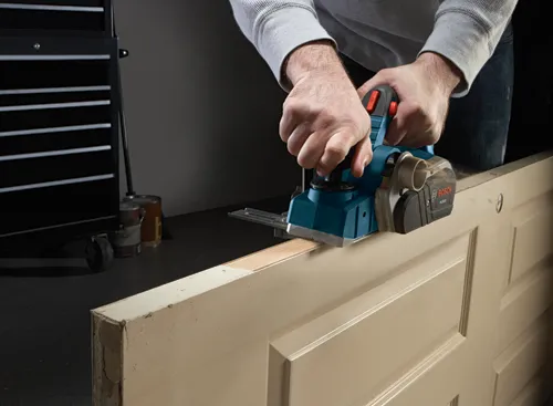Person using a Bosch PL2632 planer on a door.