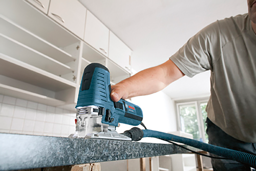Person holding a Bosch power tool near a countertop.