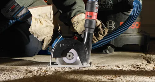 Bosch power tool cutting concrete, connected to Bosch HEPA Ready vacuum.