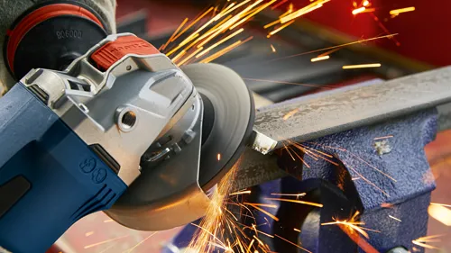 Bosch angle grinder with 806000 visible, sparks emitting during metal grinding.