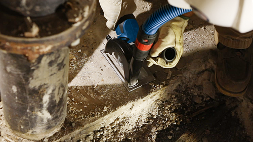 Person wearing work gloves using a circular saw on concrete.