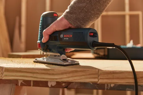 Bosch JS572EB jigsaw being held by a person over a piece of wood.