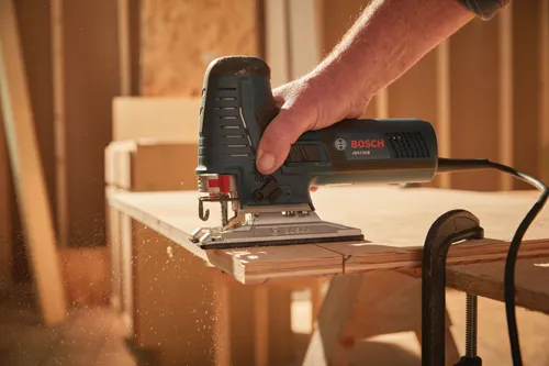 Bosch JS572EB jigsaw cutting wood; hand of a person holding the tool.