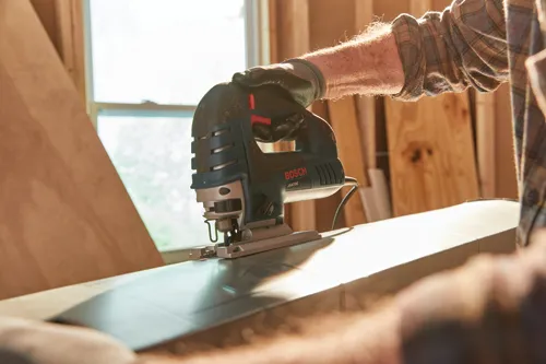 Man on a work site using the corded Bosch jig saw to cut.