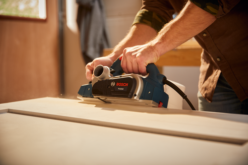 Bosch PL2632 being used on a white wooden surface, with visible dust.