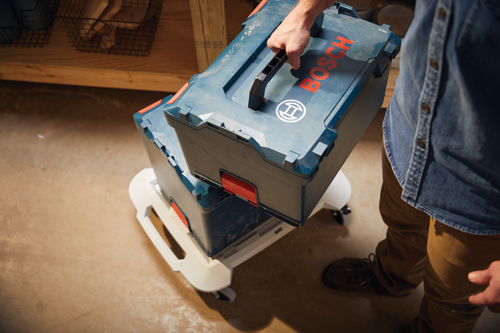 Person holding two Bosch toolboxes; the top one is being lifted; the toolboxes are on a white wheeled base.