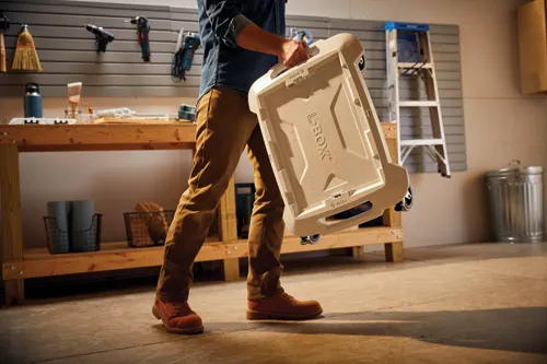 A person carries a tan L-BOXX storage container with "L-BOXX" and "BOSCH" visible.