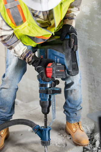 Person wearing a safety vest and gloves using a Bosch H18V-45C TURBO brushless rotary hammer with a CORE18V.12 battery to break concrete.