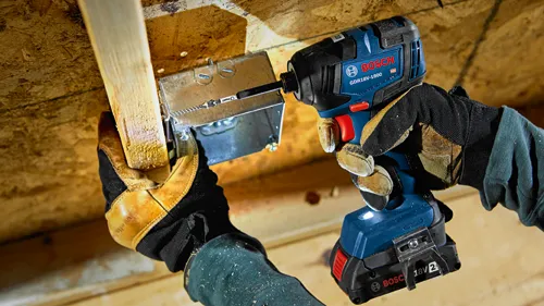 Bosch GDR18V-1800 impact driver is used to screw a metal box to a wooden beam; hands wear gloves.