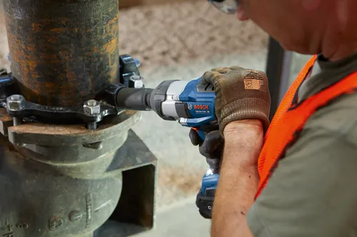 Bosch GDS18V-770C 18V impact wrench in use by person wearing work gloves and safety vest.