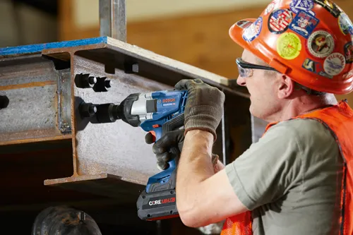 Bosch GDS18V-770C HO impact wrench, a worker in safety gear using the tool on a steel structure.