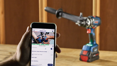 Person holding phone displaying Bosch GSR18V-1330C, connected to drill, Electronic Angle Detection, and Custom User Angle 30°, with a Bosch drill in the background.