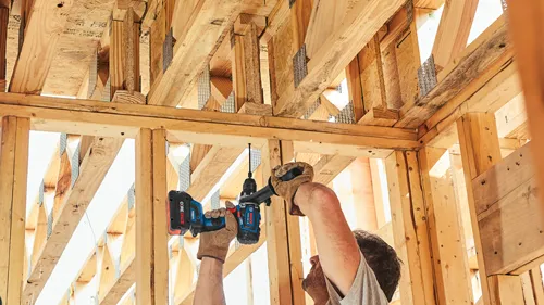 Bosch cordless drill GSR18V-LEISC being used by a person in a wooden structure.