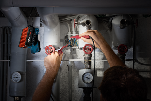 Man using the Bosch cordless worklight hanging from a hook to illuminate his work area.