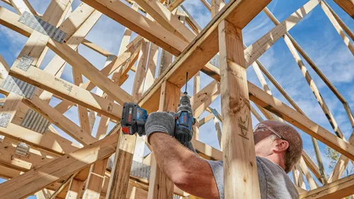 Bosch cordless drill GSB18V-1310C, used by a person to build a wooden structure, with "CORE 18V" battery.