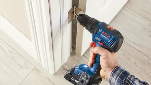 Bosch GSB18V-490 HD cordless drill being used to install a door hinge.