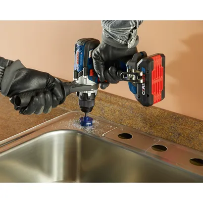 Bosch GSR18V-975C HD drill is drilling a hole in a metal sink.
