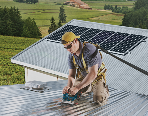 Person on roof, installing solar panels, uses a Bosch cordless jigsaw.