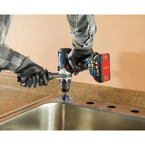 Bosch GSB18V-975C HD drill with a hole saw cutting a hole in a metal sink.