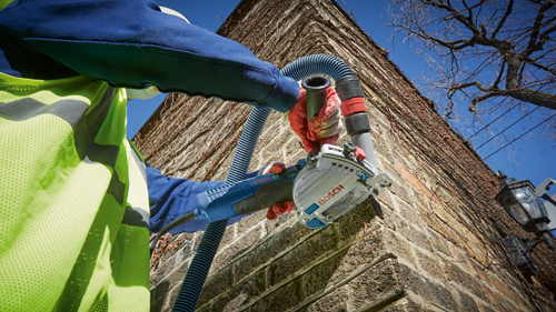 Bosch electric saw being used on brick wall.