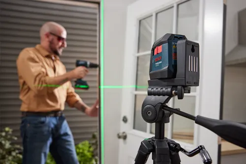 Bosch Professional GLL 50-20G laser level on a tripod, with a person holding a drill.
