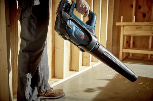 Bosch CORE18V cordless blower held by a person. The text "BOSCH" is visible on the blower.