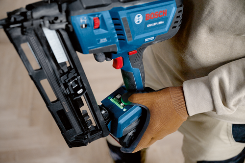 Bosch GNH18V-16MA cordless nailer held by a person wearing a brown work glove.
