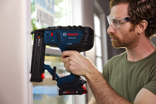 Bosch GNH18V-18M 18-GA Brad Nailer being used by a person wearing safety glasses.