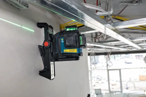 Bosch laser level tool, mounted on a wall with green laser line visible, with text "Canada ICES-003(B)/NMB-003 (B)", "IEC 60825-1-2014 <10 mW, 500-540 nm", and laser safety warning.