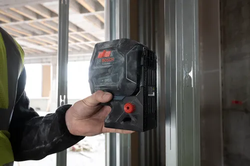 Bosch Professional GCL165-42G green laser level held by person wearing a safety vest.