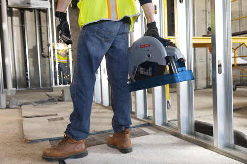 Bosch cut-off saw, with visible "BOSCH" brand name, held by a person in a construction site.