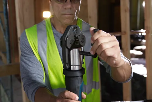 Bosch CUSS 1/2" tool, model GPT50050C1USS, being operated by a person wearing safety glasses and a high-visibility vest.