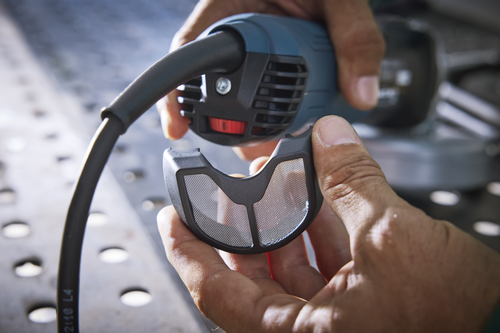 Person holding an electric power tool with a black and gray filter attachment.