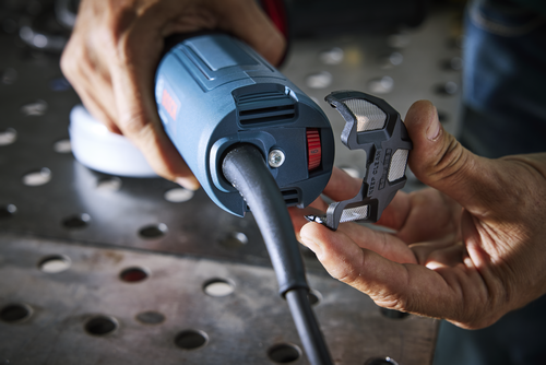 Bosch power tool with the filter component being removed, the text “KEEP CLEAN” is visible. The tool has a red switch, and the hands are those of a person with tanned skin.