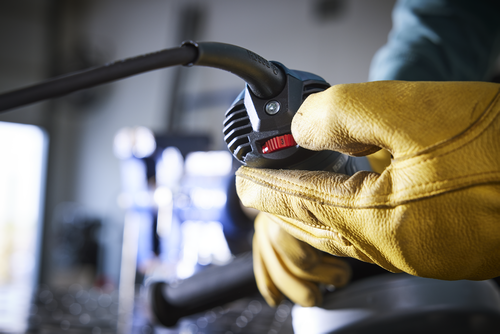 A gloved hand adjusts a speed dial on a power tool, the dial reads "3".