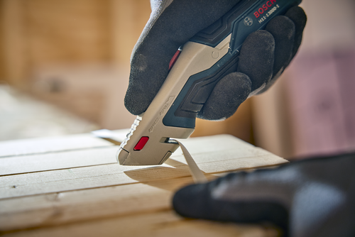 A person using the Bosch H11-13000-1 Retractable knife cutting a wood material.
