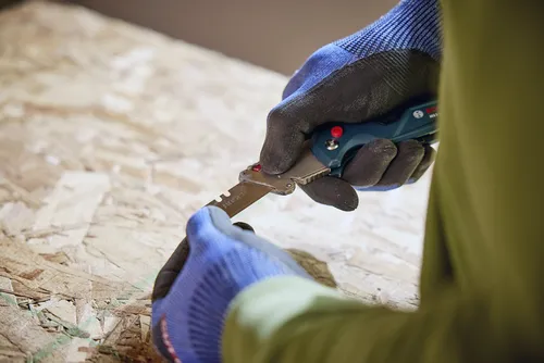 A person holding the Bosch H11-11100-1 folding knife replacing the blade.