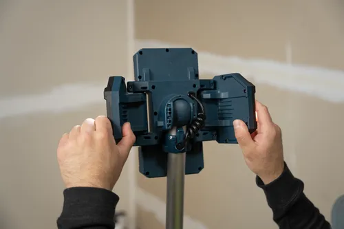 The close-up image of a worker redirecting the adjustable lamp head of Bosch GLT18V-5000N 18V Tower Light.