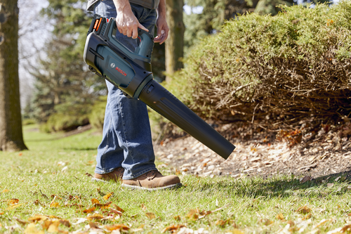 A worker using the Bosch GBL18V-450N PROFACTOR™ 18V Blower to blow the dry leaf from the garden.