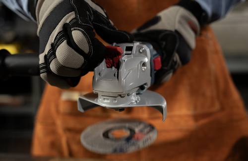 The worker releasing the disc of the Bosch GWX18V-8-2N 18V X-LOCK Brushless 4-1/2 In. Angle Grinder with Slide Switch.
