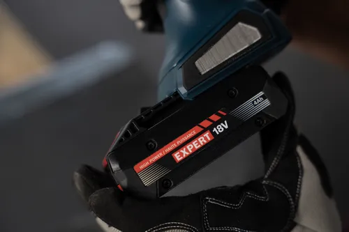 A worker attaching a Bosch EXBA18V-40 EXPERT 18V Lithium-Ion 4 Ah High Power Battery to a power tool.