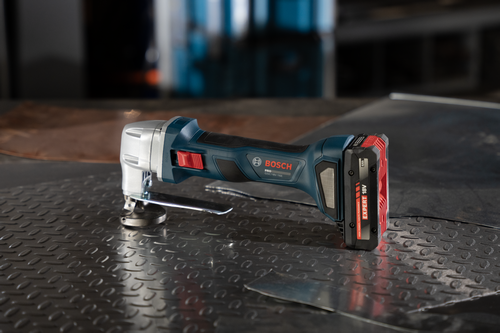 The Bosch GSC18V-16EN 18V 16-Gauge Metal Shear with Lock- On Slide Switch on a metal table with a battery.